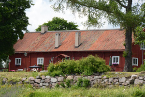 Bilden visar en gammal faluröd byggnad och stenmur. Bilden är från Kungsudden, ett exempel på en kulturmiljö i Kungsör-