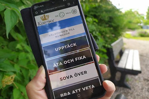 Mobiltelefon som visar startsidan för visitkungsor.se